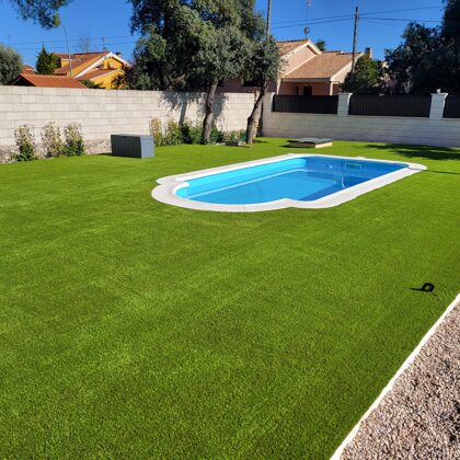 Jardin con césped artificial en  Eurovillas alrededor de la piscina
